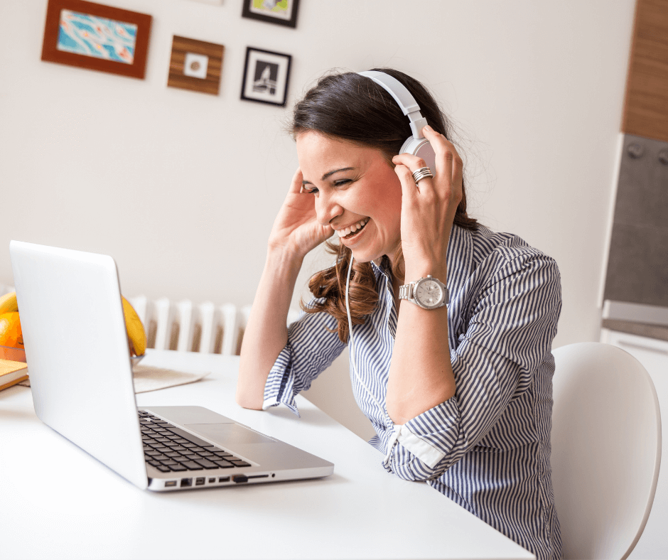 language student laughing and listening to a French class on her open laptop with headphones on