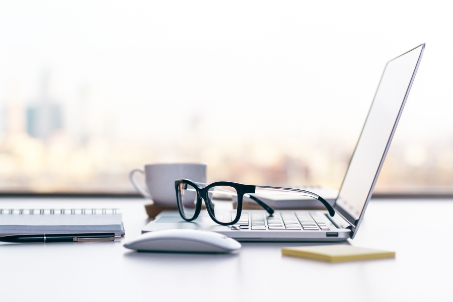 an open laptop with an expresso cup and a pair of glasses