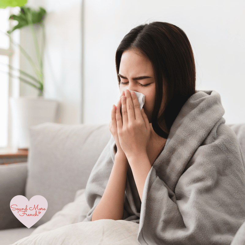 2 A woman wrapped in a blanket on a sofa, blowing her nose – representing symptoms like a cold or flu.