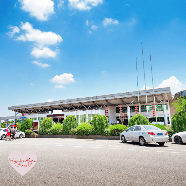 4 A sunny day at a French motorway service station, with parked cars and travellers taking a break on their holiday journey.