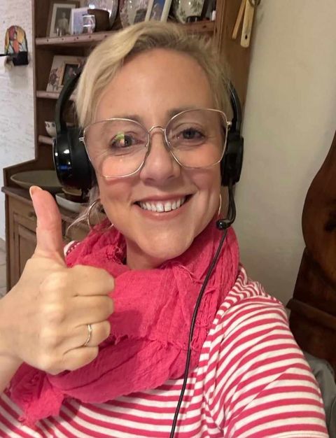 Judith smiling_woman_in_pink_and_white_striped_top_and_headset_doing_thumbs_up_to_camera