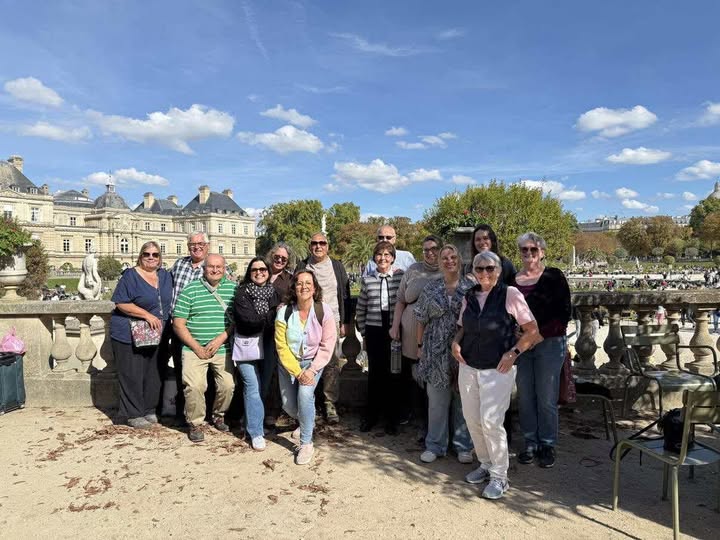 The_Café_Cats_in_Paris_group_smiling_together_in_the_Jardin_du_Luxembourg_with_the_French_Senate_building_in_the_background