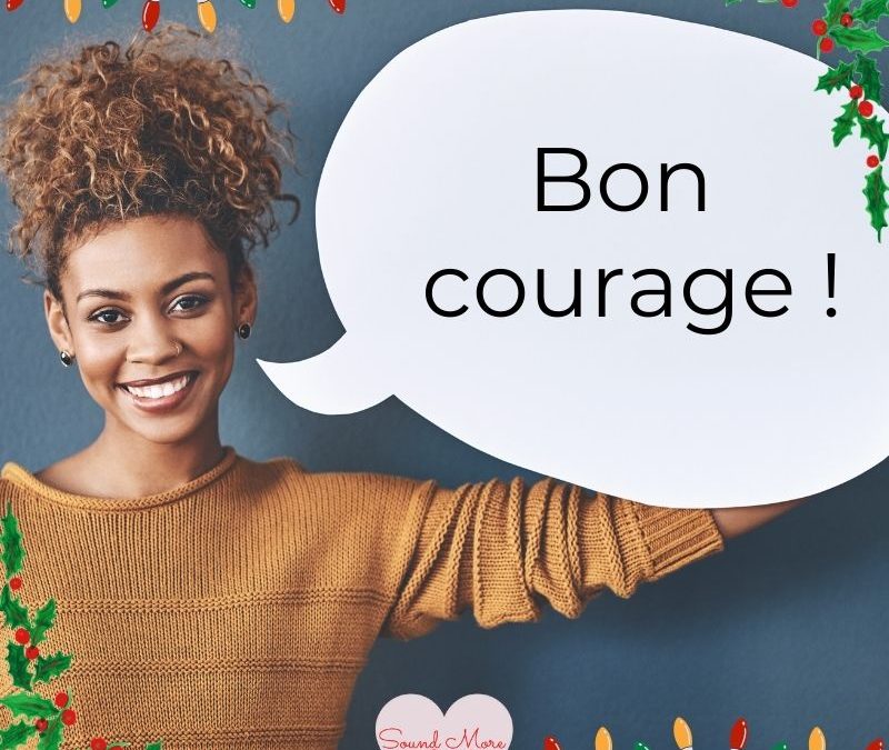smiling_woman_holding_speech_bubble_with_text_bon_courage_surrounded_by_christmas_lights_and_holly_sound_more_french_logo_visible