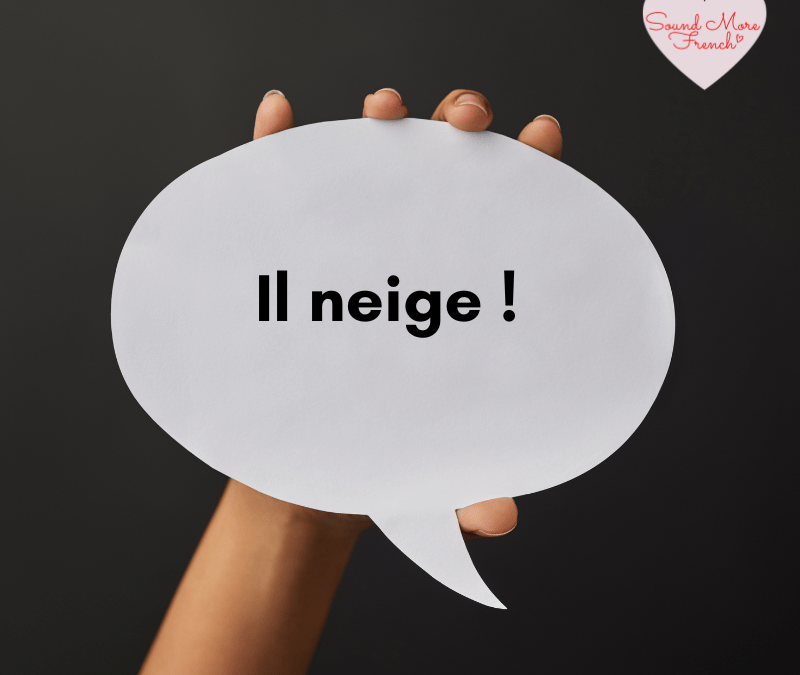 Hand_holding_a_white_speech_bubble_with_the_French_phrase_il_neige_written_in_black_text_on_a_dark_background