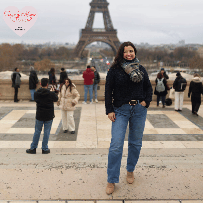 Frannie_standing_confidently_near_the_Eiffel_Tower_in_Paris_wearing_a_dark_jumper_scarf_jeans_and_ankle_boots_with_tourists_and_the_river_visible_behind_her
