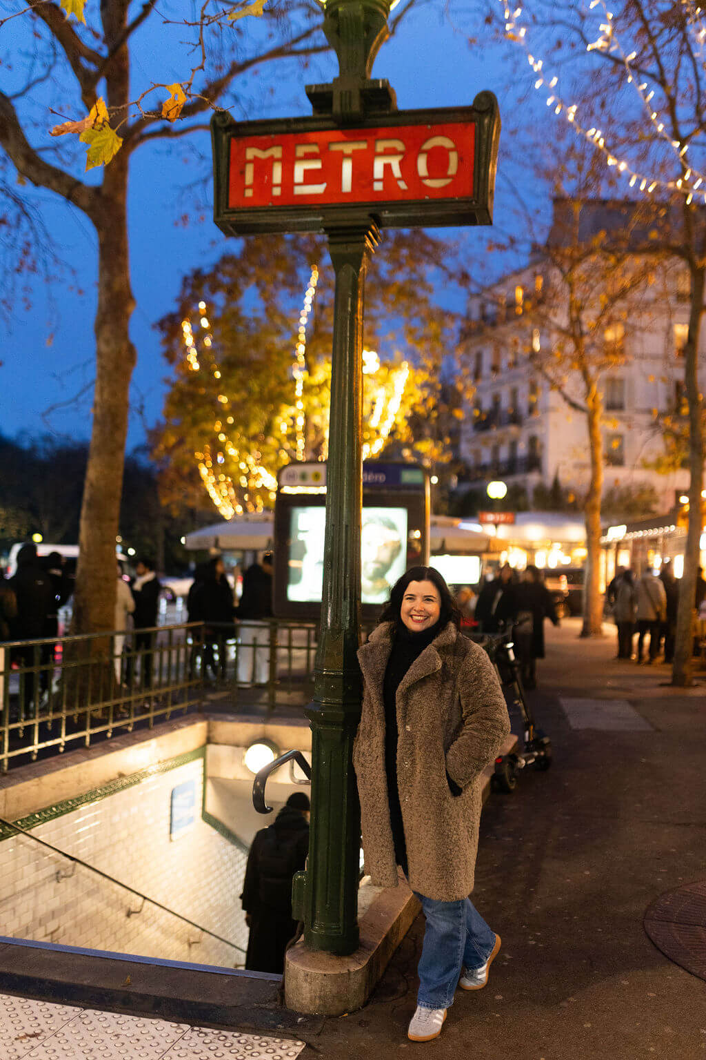 Metro 3 Frannie_standing_confidently_near_the_Eiffel_Tower_in_Paris_wearing_a_dark_jumper_scarf_jeans_and_ankle_boots_with_tourists_and_the_river_visible_behind_her